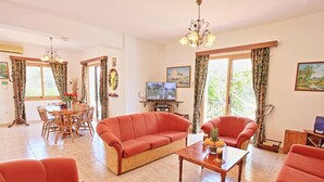 Una sala de estar amplia con sofá, sillones, una mesa de centro y un comedor con mesa y sillas.