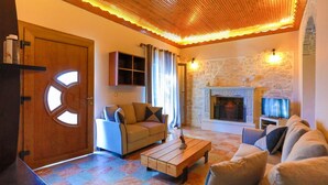 Ein gemütliches Wohnzimmer mit Kamin aus Stein, Holzboden und einem karierten Boden.