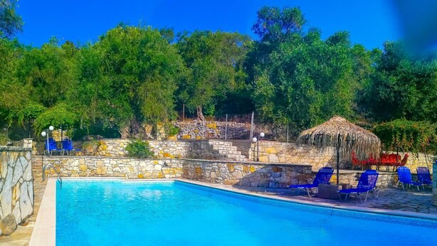 Ein Schwimmbecken mit Steinwänden und blauen Liegestühlen.