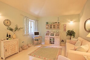 Una sala acogedora con un sofá, un mueble de madera, un televisor y una ventana con cortinas.
