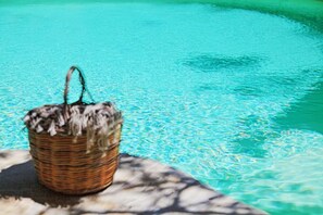 Un cesto di vimini pieno di oggetti vicino a una piscina.