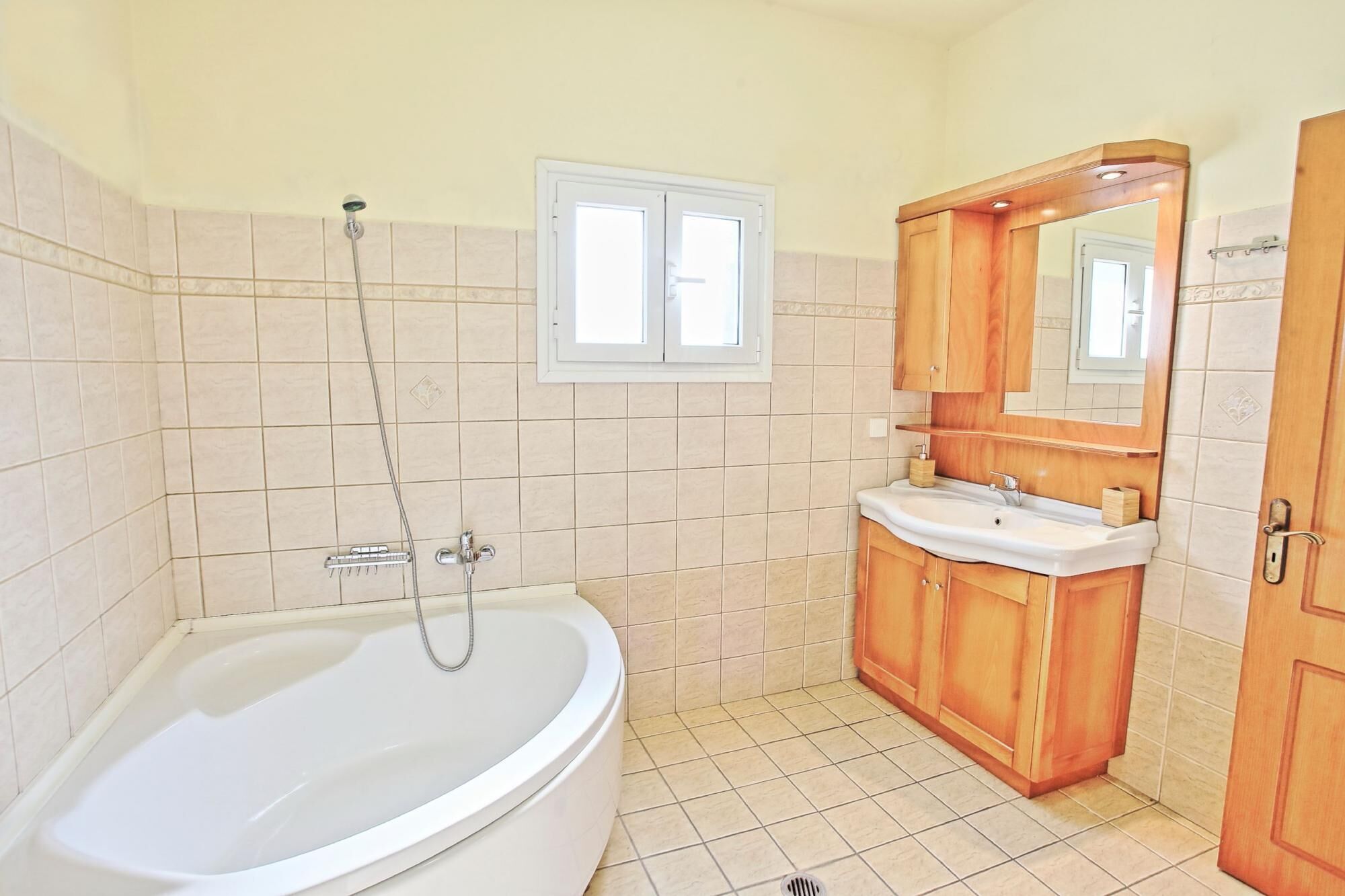Un bany amb banyera, un lavabo i un tocador de fusta.
