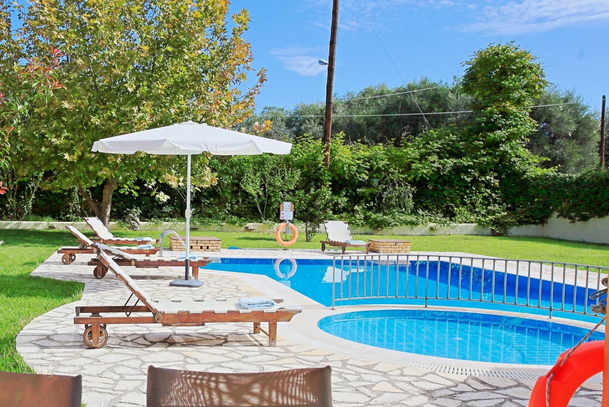 Une piscine avec des chaises longues et un parasol.