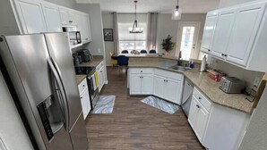 A modern kitchen with white cabinets, stainless steel appliances, and a central island.