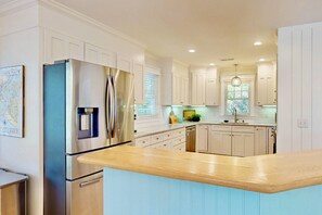 Una cocina moderna con armarios blancos, electrodomésticos de acero inoxidable y encimera de madera.