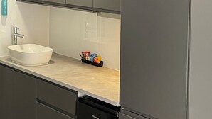 A modern kitchen with a white sink, grey cabinets, and a black dishwasher. - Barham Bridge Motor Inn (Barham)