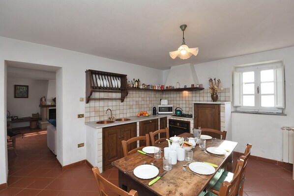 A kitchen with a wooden table set for dining, a microwave, and a stove.