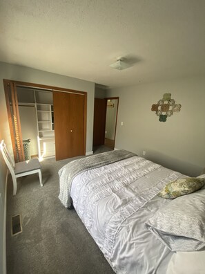 A bedroom with a bed, a chair, a wardrobe, and a mirror.