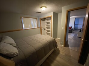 Cozy retreat with a single bed, window with blinds, and a door leading to another area.