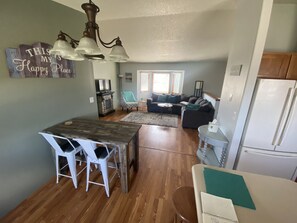 A modern kitchen with a dining area, wooden flooring, and a chandelier.