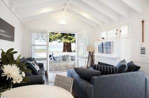 A modern living room with a large window, a sofa, a coffee table, and a TV mounted on the wall.