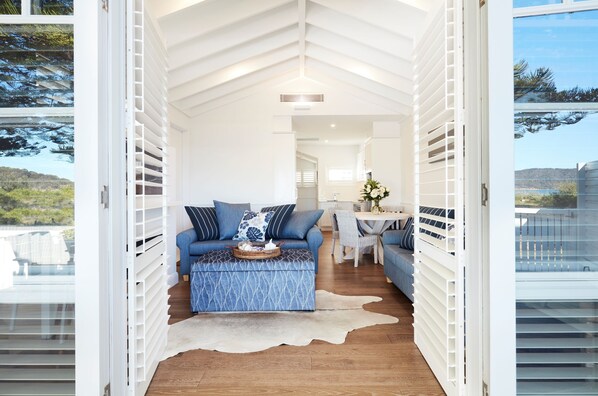 A modern interior with a blue patterned sofa, a white coffee table, and a dining area with a white table and chairs.
