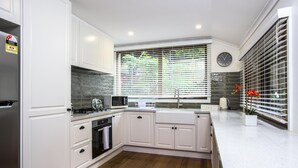 Una cocina moderna con armarios blancos, un refrigerador de acero inoxidable, un microondas y un lavamanos.