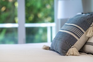 Lähikuva sängystä, jossa on kuviollinen tyyny ja koristeellinen tupsu.