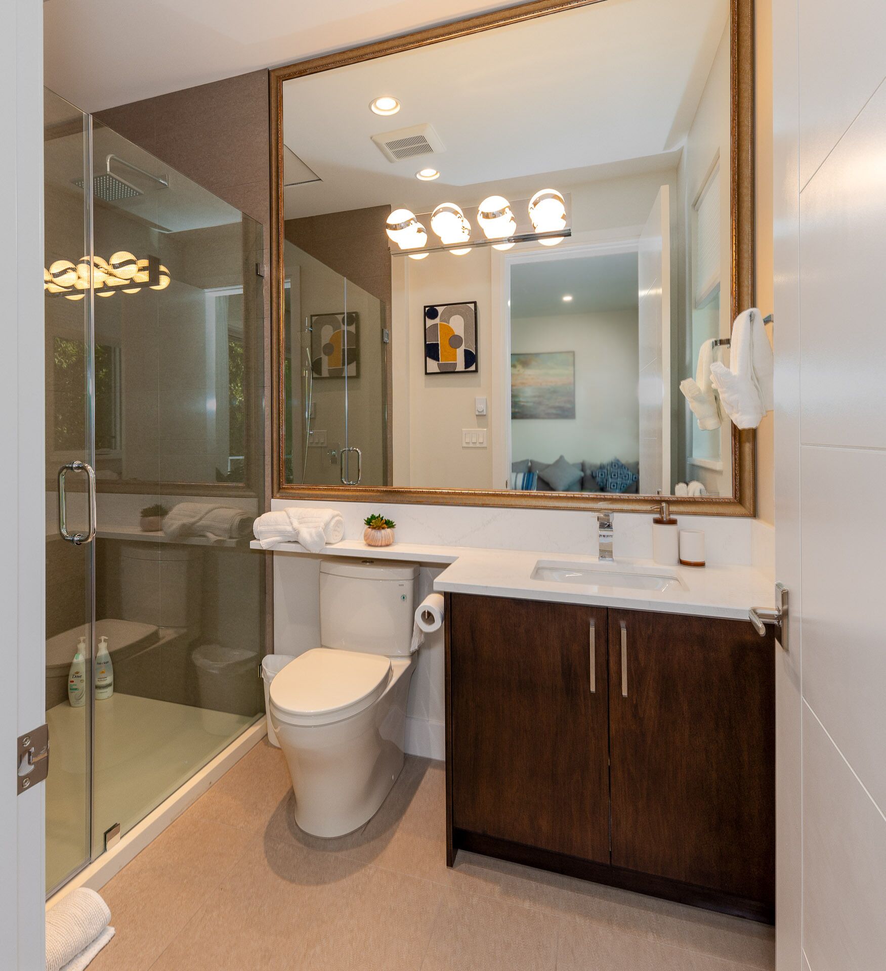 A modern bathroom with a glass shower enclosure, a white toilet, a vanity with a mirror, and a sink.