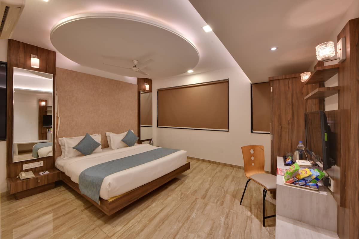 A modern hotel room with a bed, a desk, a chair, and a mirror.