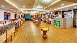 Un restaurante con una barra alargada, suelo de madera y una urna decorativa en el centro.