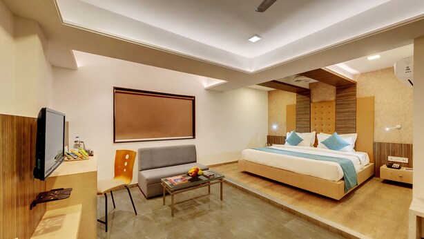 Una habitación de hotel moderna con cama, sofá, televisor y mesa de centro.