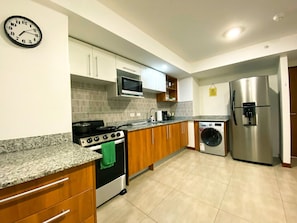A modern kitchen with a stove, oven, microwave, washing machine, and refrigerator.