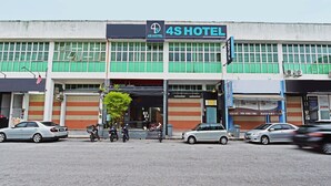 Ett 4-stjärnigt hotell med en stor skylt, många fönster och en parkeringsplats med flera bilar och motorcyklar.