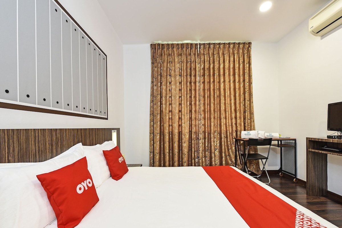 Ein Hotelzimmer mit Bett, Schreibtisch, Stuhl, Klimaanlage und Vorhang.