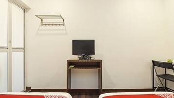 A hotel room with two beds, a TV on a wooden stand, a small shelf, and a window.