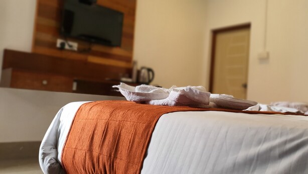 Ein Hotelzimmer mit einem Bett, einem an der Wand befestigten Fernseher und einer Tür im Hintergrund.
