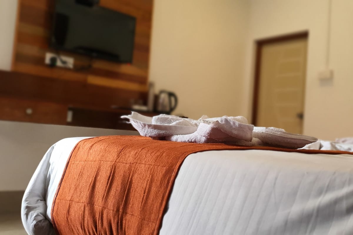 A hotel room with a bed, a television mounted on the wall, and a door in the background.