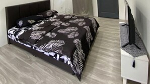 A bedroom with a bed, a ceiling fan, a TV, and a door. - OYO Homes 90650 Na Homesuite (Ranau)