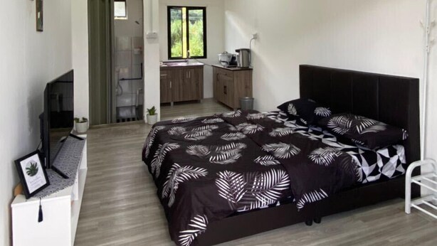 A modern bedroom with a bed, a TV, a ceiling fan, a small desk, and a window. - OYO Homes 90650 Na Homesuite (Ranau)