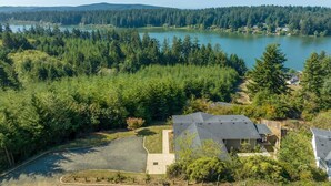 Una zona residencial con una casa, un camino de entrada y un lago rodeado de bosque denso.