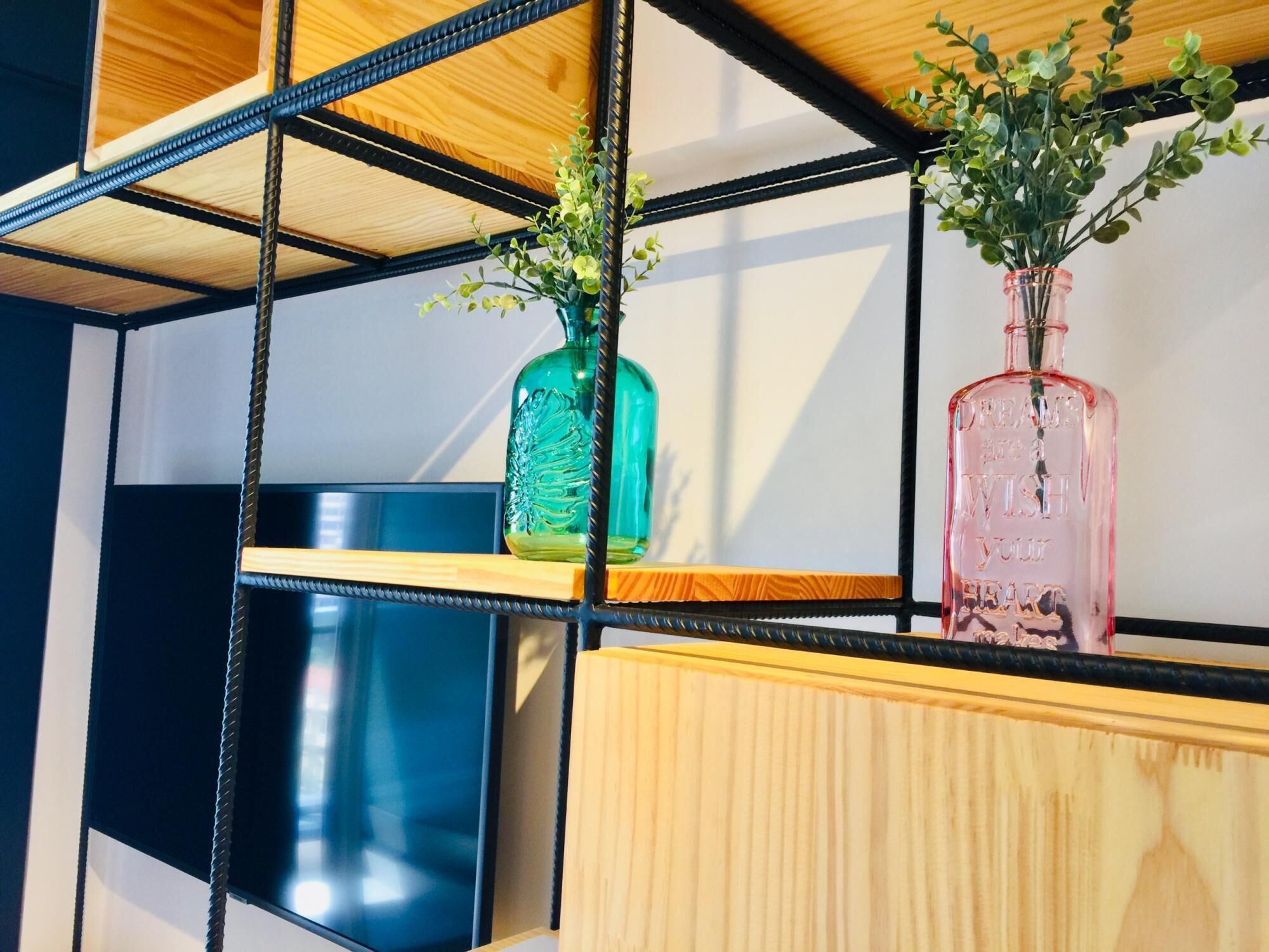 A shelf with two glass bottles and a small plant.