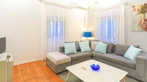 A modern living room with a grey sectional sofa, a white coffee table, and a lamp. - Villa Regina in Kentroma (Corfu)