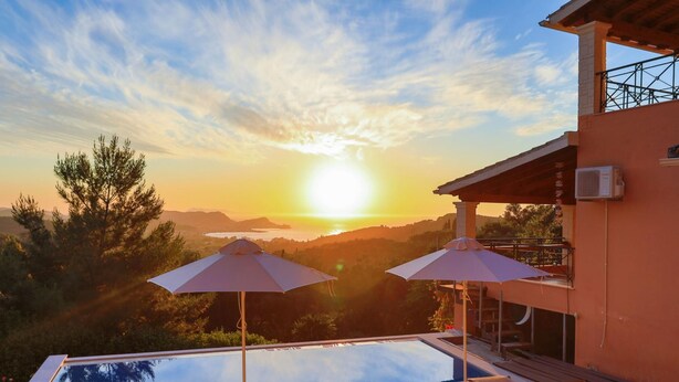 A swimming pool with lounge chairs and umbrellas, overlooking a scenic sunset view. - Sunset House in Sidari (Corfu)