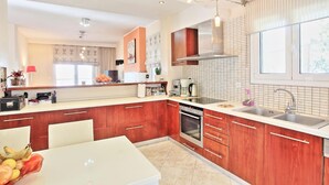 A modern kitchen with wooden cabinets, a white countertop, and a stainless steel sink. - Sunset House in Sidari (Corfu)