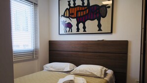 A neatly made bed with a beige quilt, two white pillows, and folded towels on the bed. - Ofp1312 Duplex Oscar Freire (São Paulo)