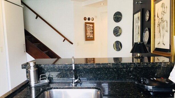 A kitchen with a stainless steel sink, a coffee machine, and a black countertop. - Ofp1312 Duplex Oscar Freire (São Paulo)
