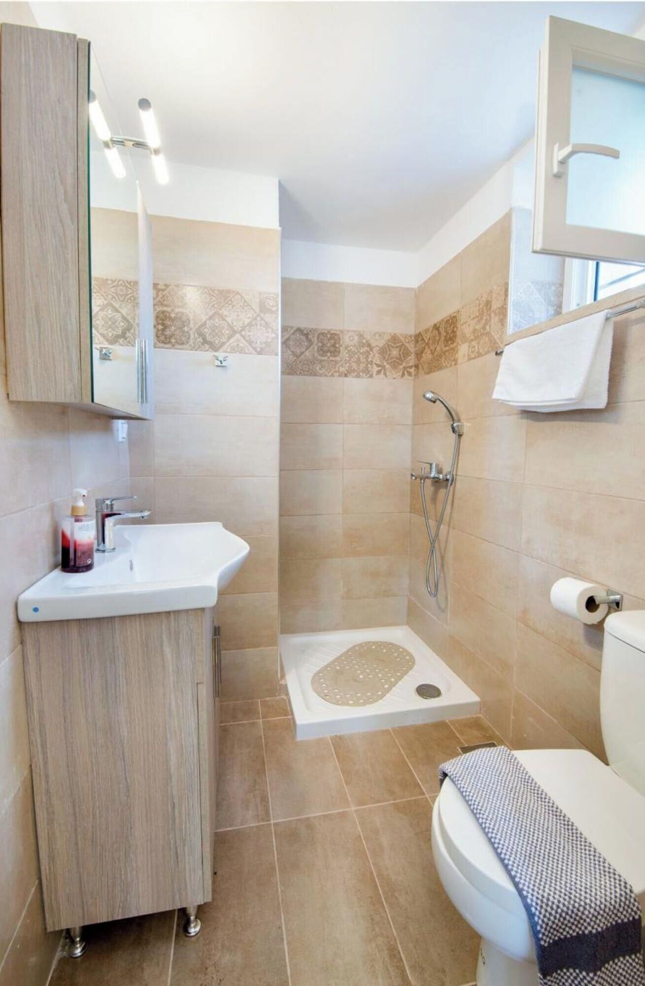 A bathroom with a shower, toilet, sink, and a mirror.