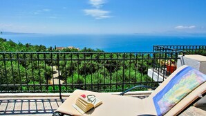 A balcony with a view of the sea, a lounge chair, and a book. - Villa Alexandros in Nisaki (Corfu)
