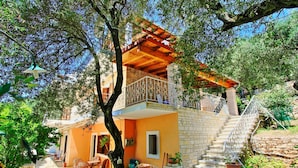 A two-story house with a balcony, a staircase, and a patio area with outdoor furniture. - Villa Alexandros in Nisaki (Corfu)