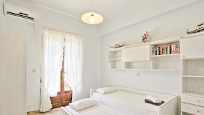 A room with two single beds, a bookshelf, and a window with curtains. - Villa Alexandros in Nisaki (Corfu)