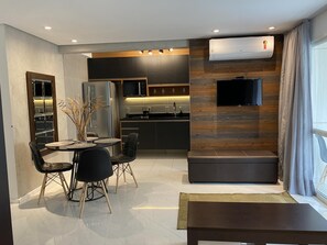 A modern kitchen with dark cabinetry, a built-in microwave, and a flat-screen TV mounted on the wall. - Pg596-73b in S o Paulo (São Paulo)