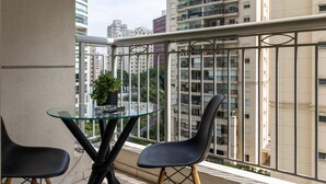 Ein Balkon mit Glastisch und zwei Stühlen, mit Blick auf eine Skyline mit Hochhäusern.