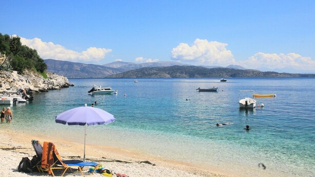 A beach with clear water, boats, and a mountainous backdrop. - Jasmin in Katavolos With 1 Bedrooms and 1 Bathrooms (Corfu)