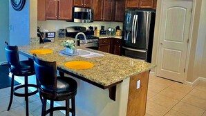 Eine moderne Küche mit Granit Arbeitsplatten, Edelstahlgeräten und Pendelleuchten.