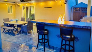 Eine Außenpatio mit Bar, Sitzgelegenheiten, Deckenventilatoren und Lichterketten.