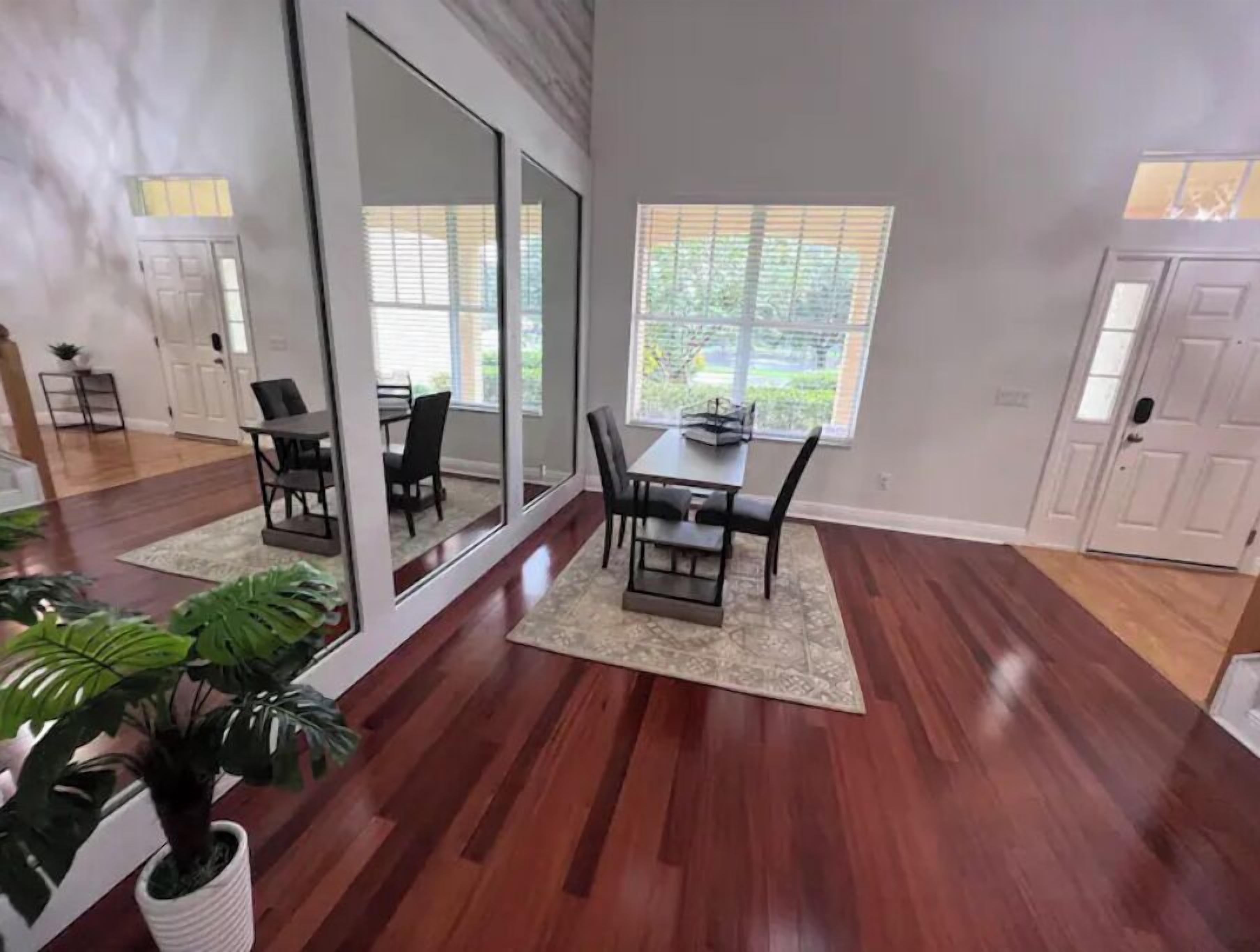 Une pièce spacieuse comprenant une table et des chaises, un grand miroir et une vue sur l’extérieur par une fenêtre.
