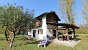 Ein rustikales Haus mit einer Holzveranda, einem Grillplatz und einem Rasen.