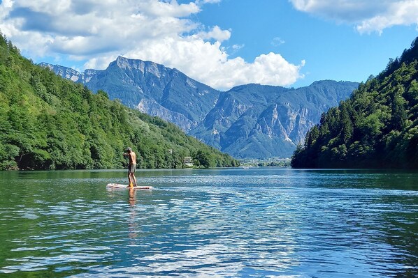 Una persona haciendo paddleboard en un lago tranquilo con montañas al fondo.