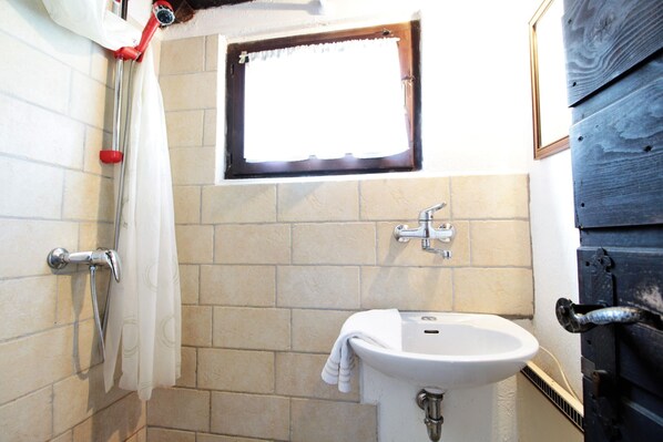 Ein Badezimmer mit Dusche, Fenster, Waschbecken und Tür.